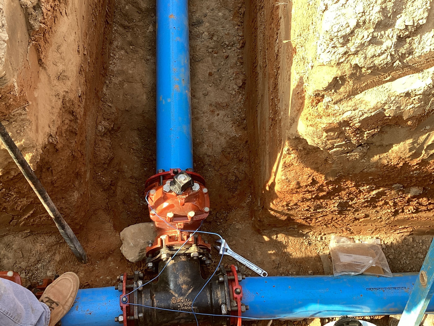 Crew member installing water line in trench