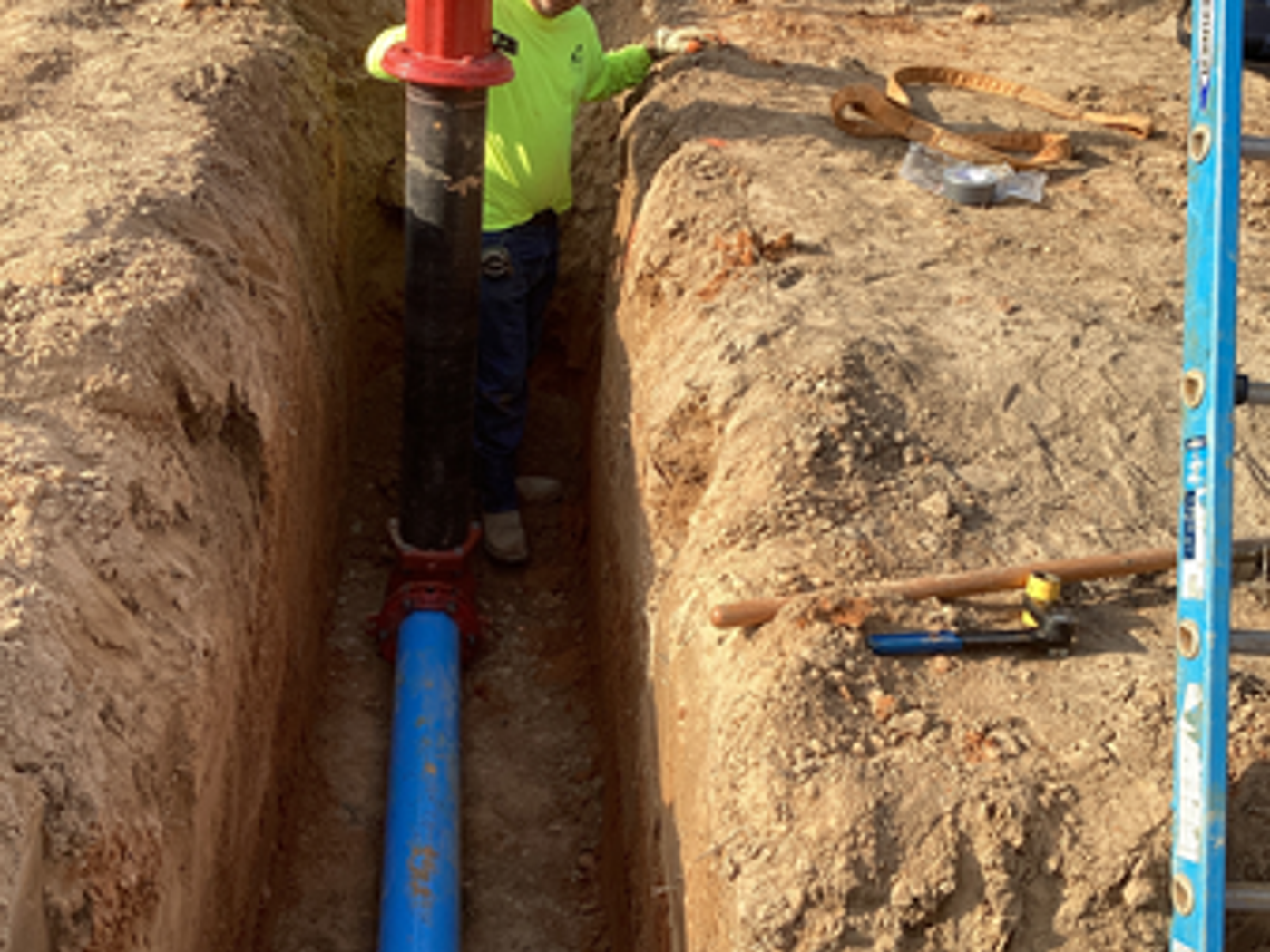 Pipe installation with trench and crew member