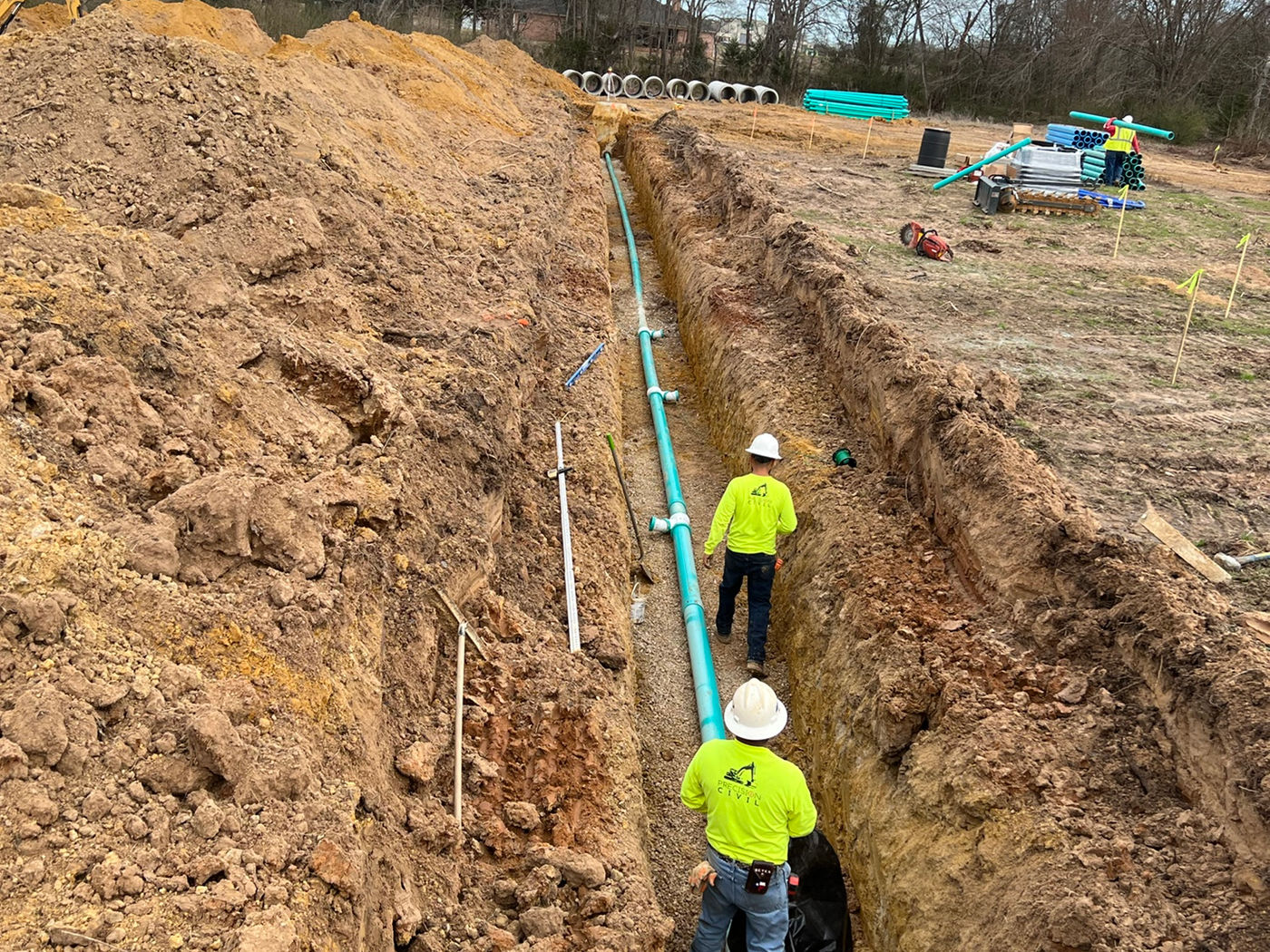Utility pipe installation with crews in trench
